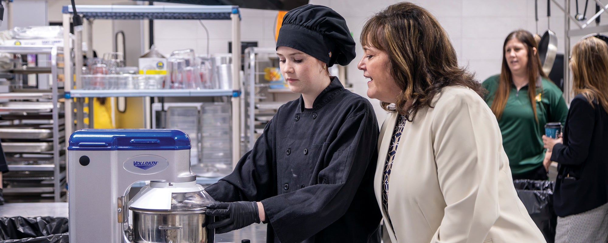Academy ISD Superintendent Darla Nolen watches a student work 
in the culinary arts kitchen.