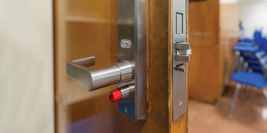 Slightly open classroom door with new security hardware and locks