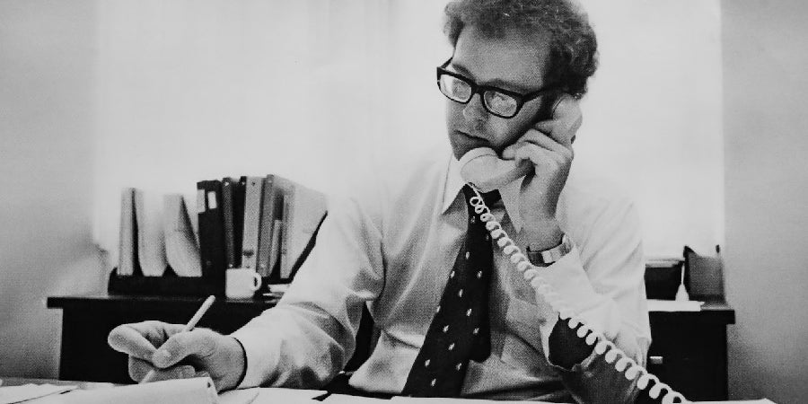 D Thompson, Government Relations Director, talking on the phone and working at desk